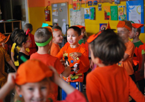 Dzieci ubrane w pomarańczowe stroje tańczą do muzyki