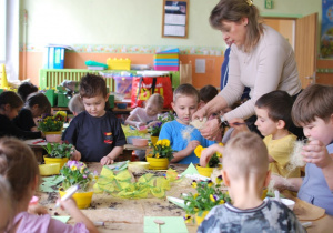 dzieci sadzą i dekorują kwiatki